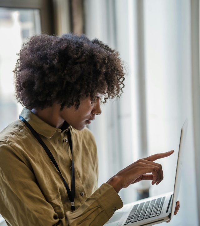 Professional woman engaged in business tasks on laptop, concentrating in a modern office.