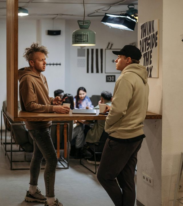 Two men in a modern office setting having a casual conversation, emphasizing teamwork.